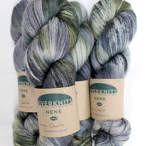 A pile of skeins of Nene 4 Ply in variegated greys, slate blue-grey, and moss green
