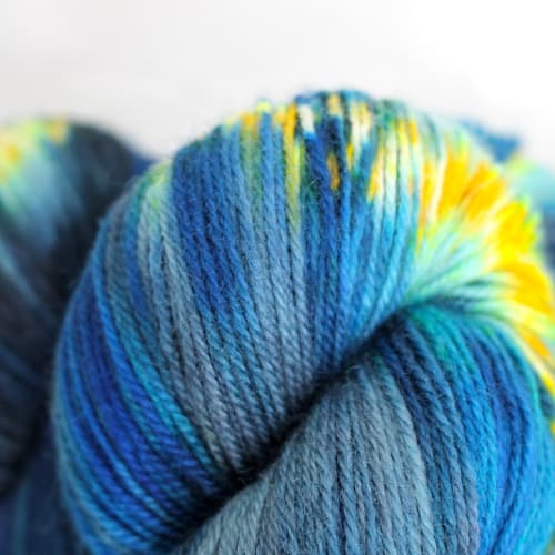 Skeins of yarn that are variegated from dark to light blue with bright yellow speckles