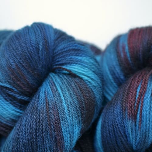 Skeins dyed in variegated dark blues with a hint of burgundy red